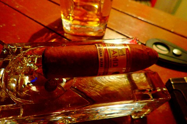 Zigarre in Aschenbecher vor Whiskyglas